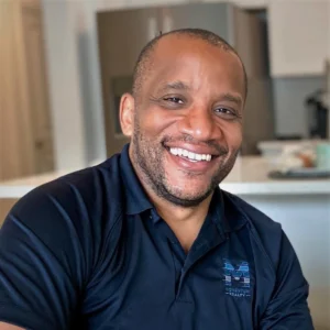 Chris Moore smiling, wearing a Momentum Realty polo shirt.